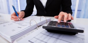 30069004 - midsection of businesswoman calculating tax at office desk