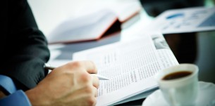 12620626 - image of male hand with pen and newspaper and cup of coffee near by